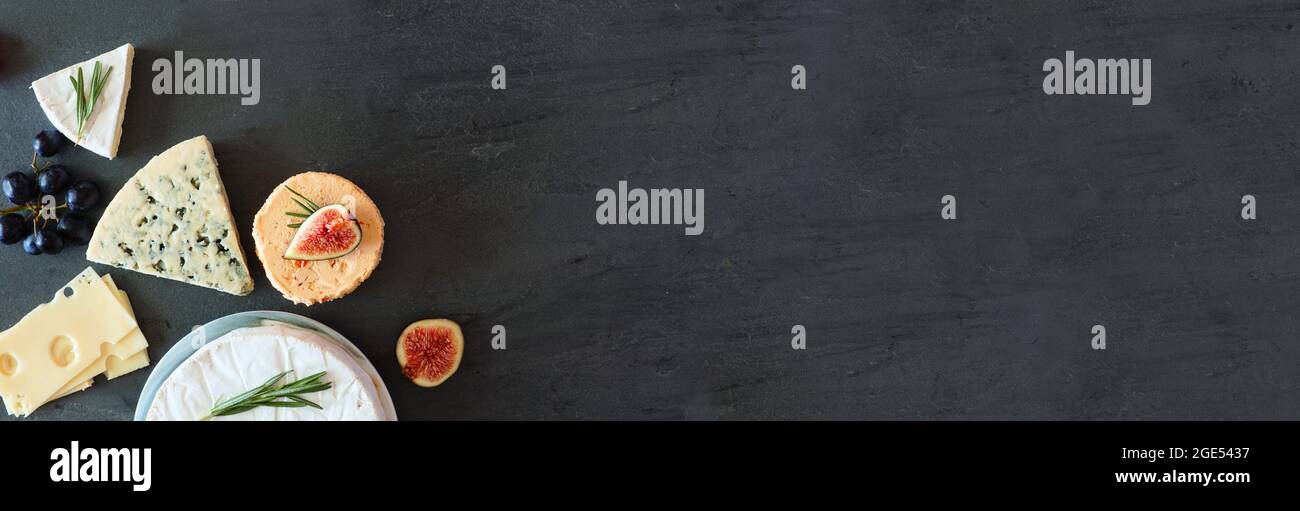 Corner border of a selection of cheeses. Top view banner on a dark stone background with copy space. Stock Photo