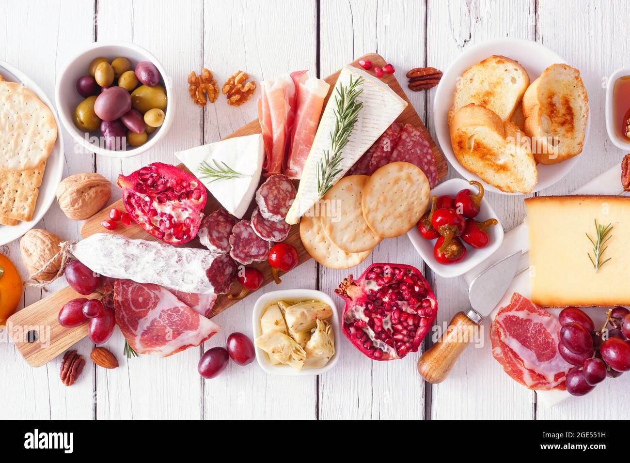 Charcuterie board of assorted cheeses, meats and appetizers. Above view table scene on a white wood background. Stock Photo
