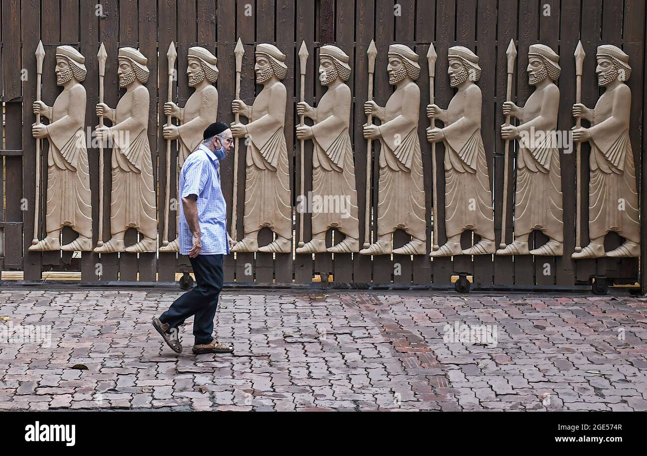 Mumbai, India. 16th Aug, 2021. A Parsi man walks past a fire temple