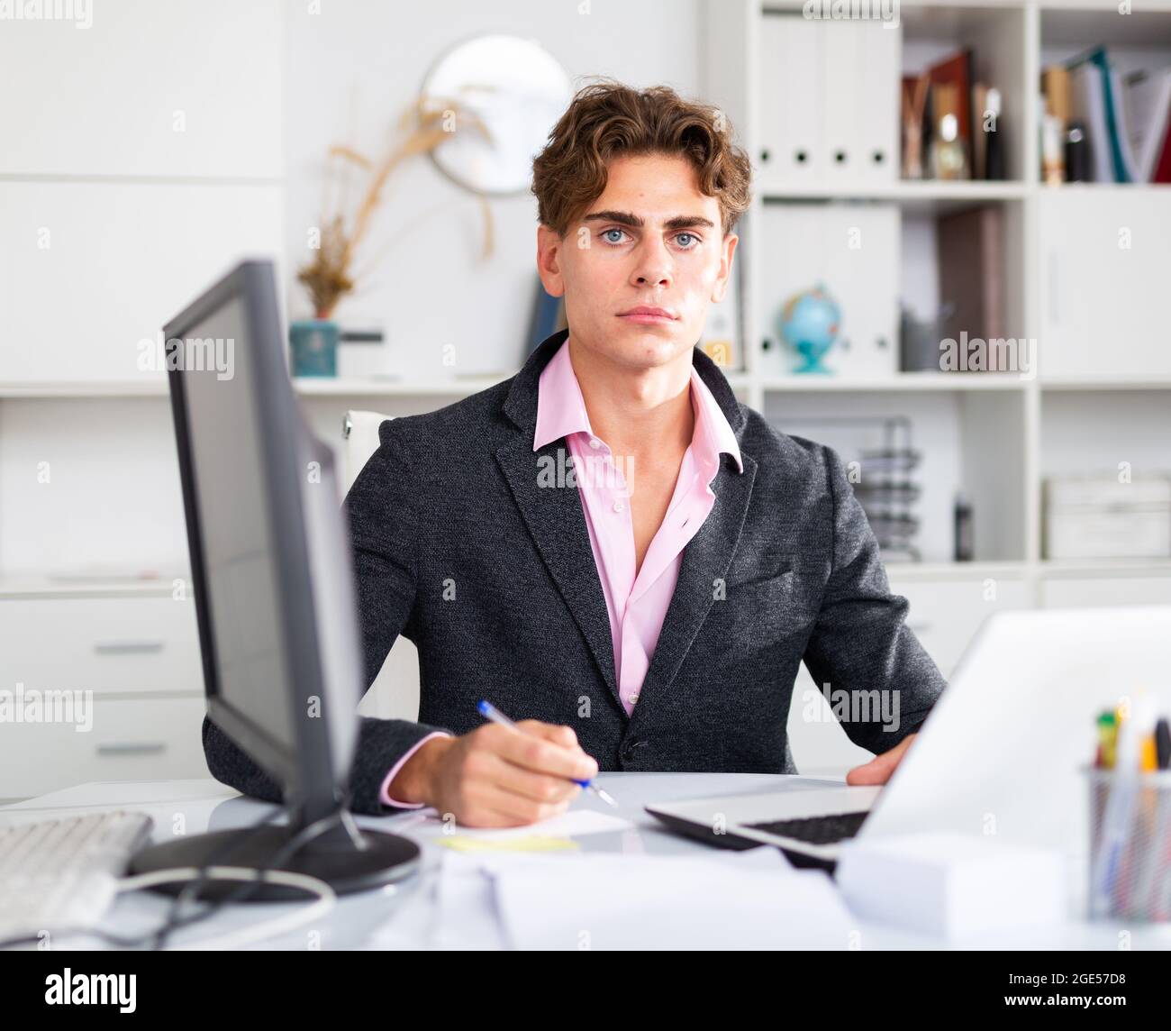 Focused attractive young man working with laptop and documents Stock Photo