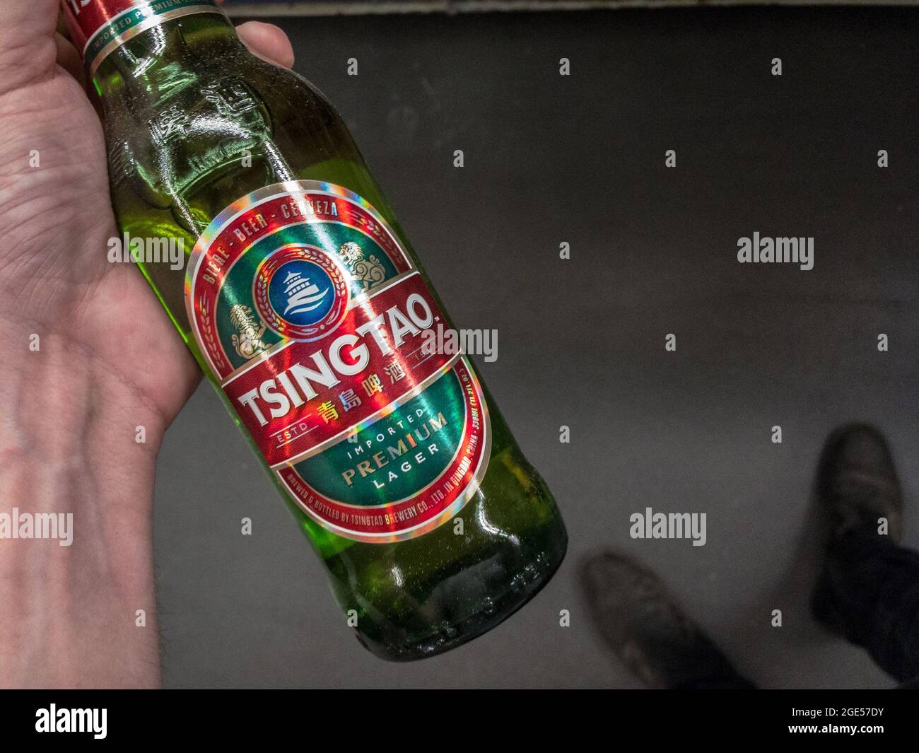 Picture of a hand holding a bottle of Tsingtao beer. Tsingtao Brewery Co. Ltd. is China's second largest brewery, with about 15% of domestic market sh Stock Photo