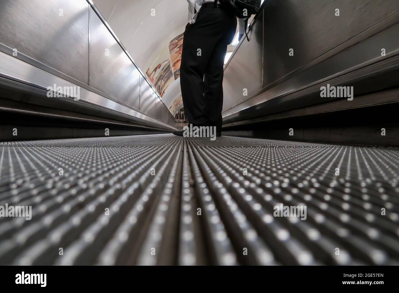 Low angle view of a male commuter standing on moving walkway Stock Photo