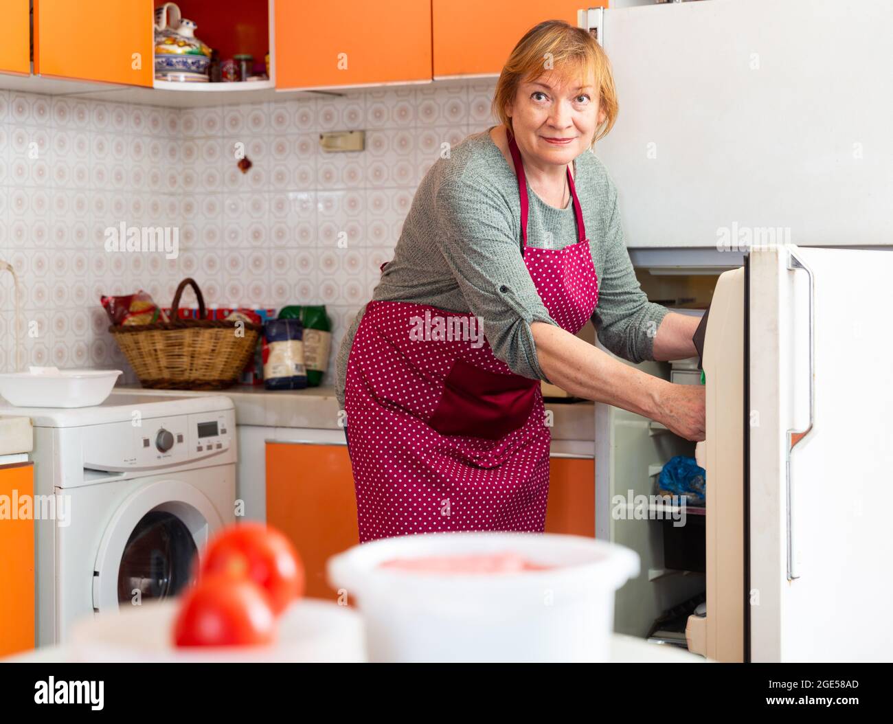 Elderly woman cooks preparing food in the kitchen Stock Photo