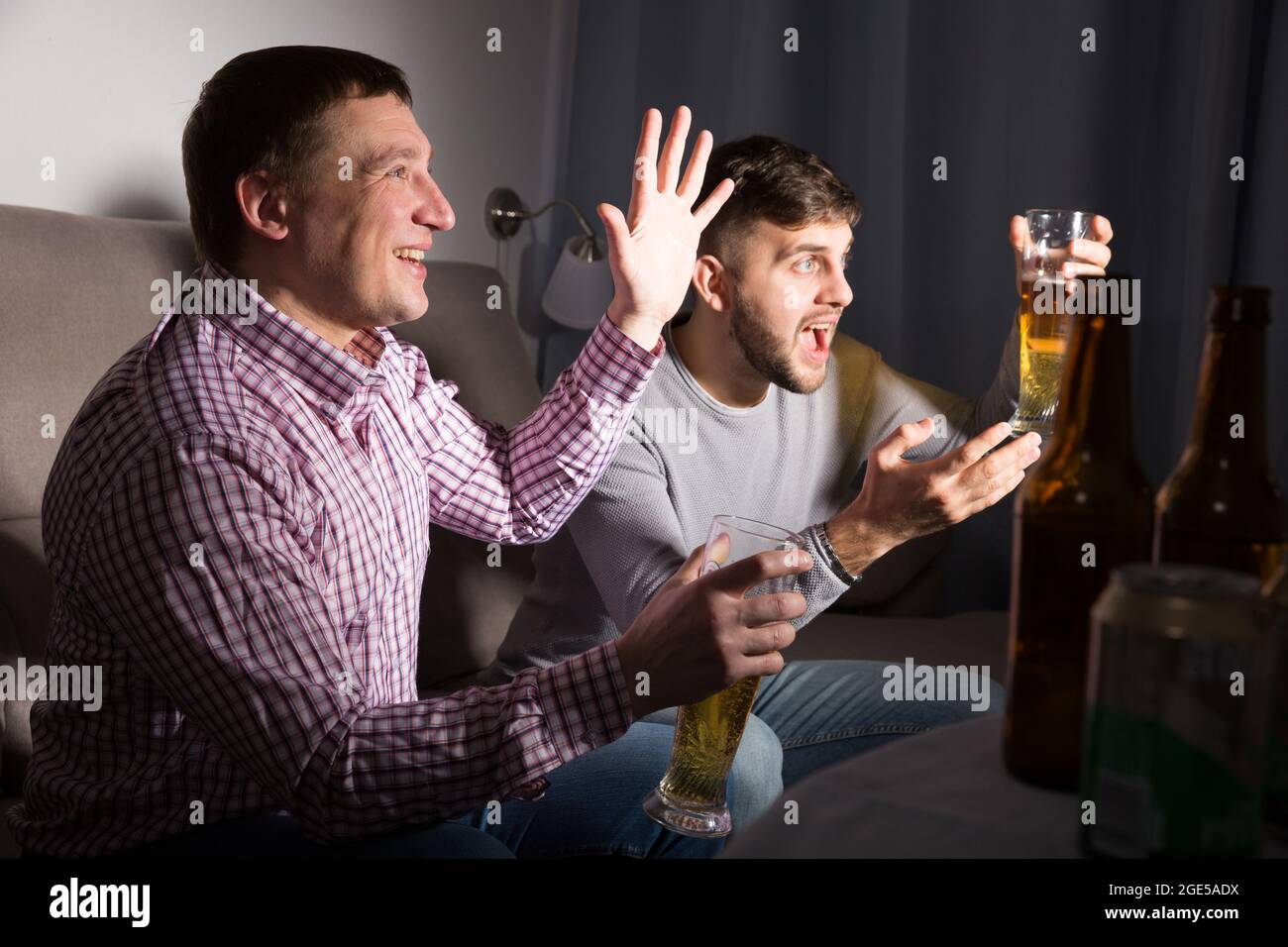 Exalted male friends watching tv at home Stock Photo