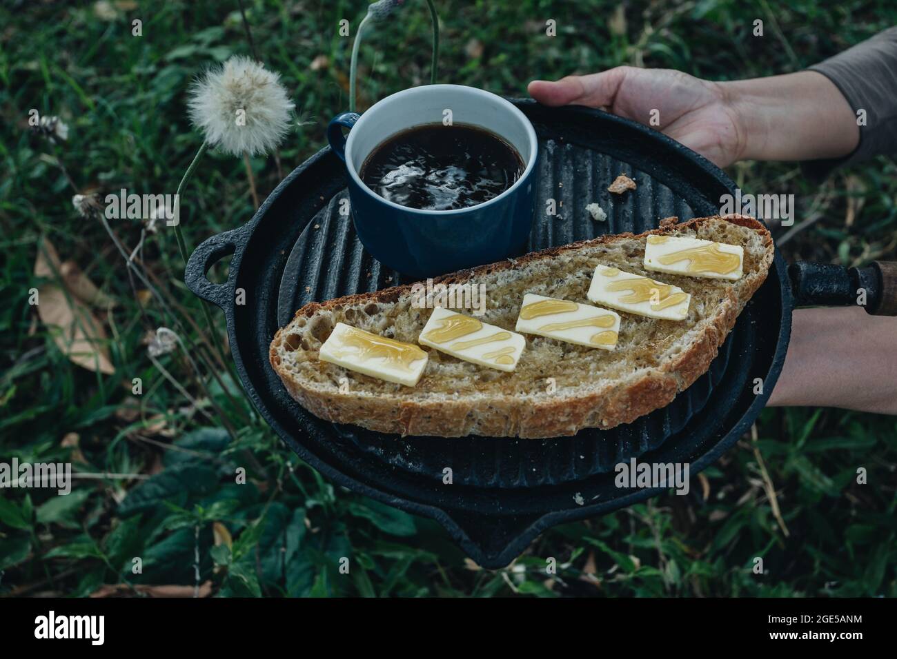 Homemade crusty open crumb artisan sourdough bread with butter and honey, cup of coffee, in the backyard, natural background Stock Photo
