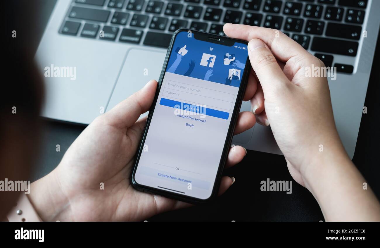 CHIANG MAI ,THAILAND - APR 10, 2021 : Woman hand holding iPhone 6S to use facebook with new login screen.Facebook is a largest social network and most Stock Photo