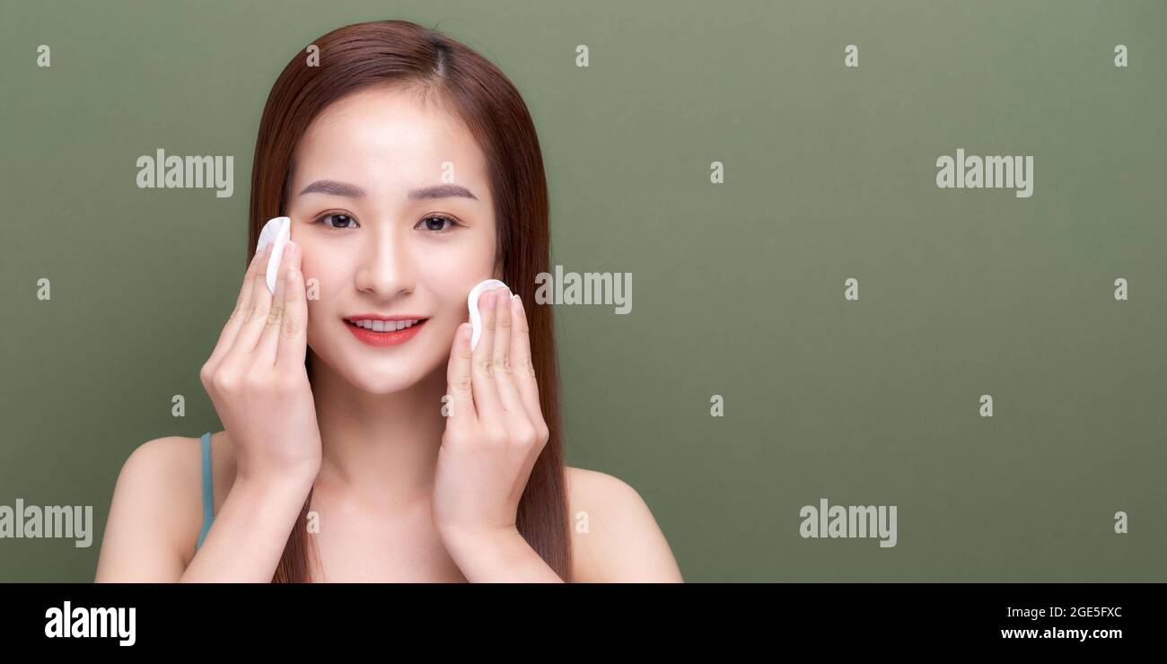 Happy smiling beautiful young woman cleaning skin by cotton pad Stock ...