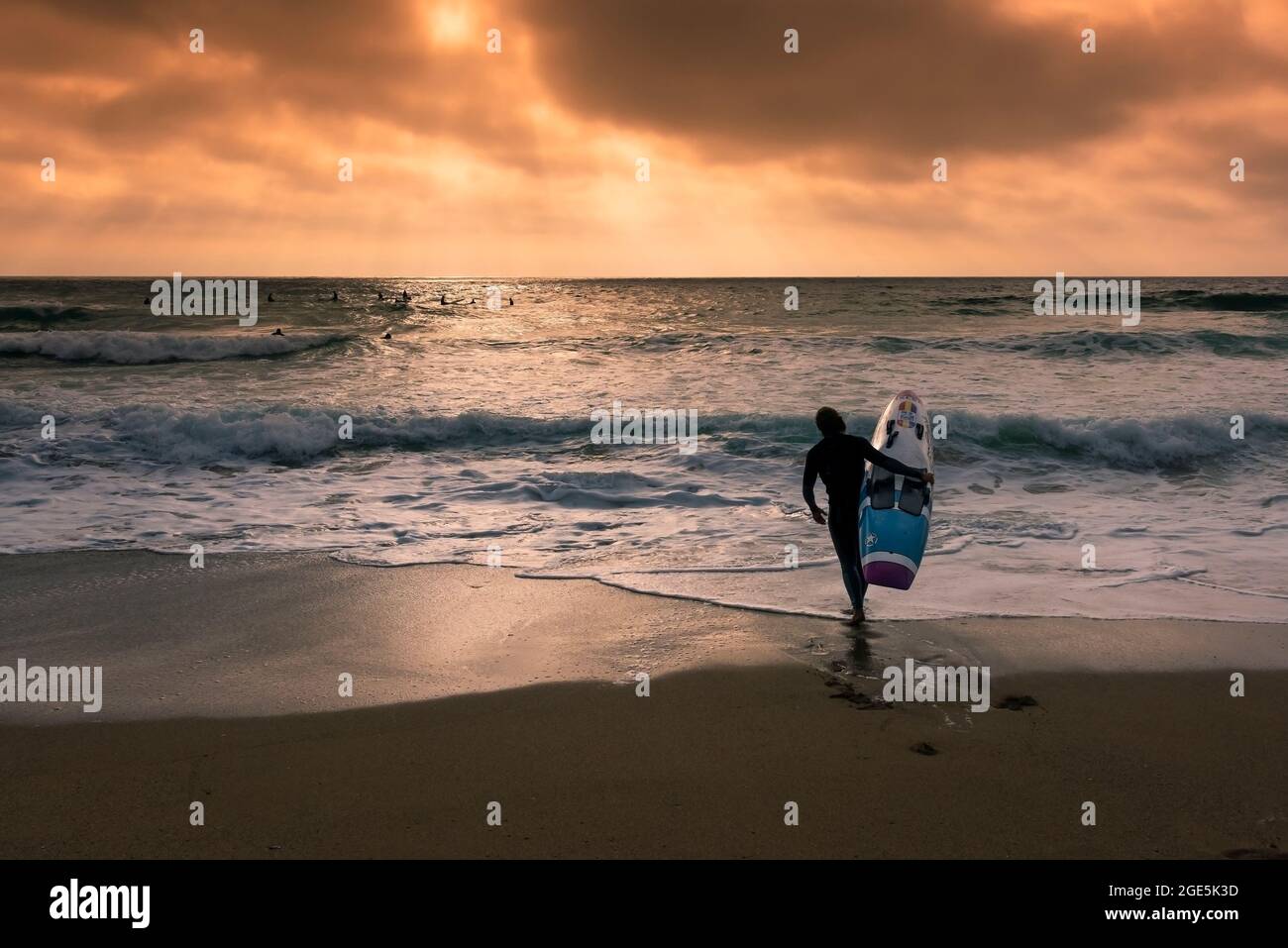 A member of Newquay Surf Lifesaving Club walking into the sea carrying Kracka Rescue board during a training session on Fistral Beach in Newquay in Co Stock Photo