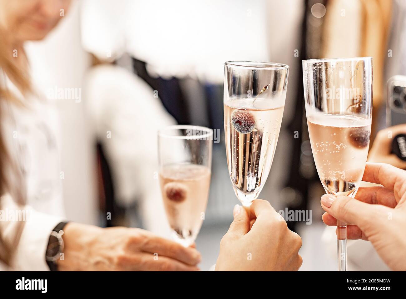 Beautiful female hands are holding glasses of champagne or rose wine. Close-up. Women clink glasses. New Years celebration, event or party. Soft focus Stock Photo