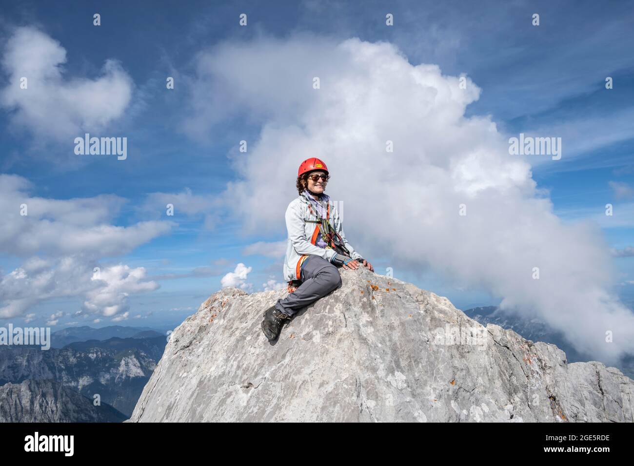 Hiker with helmet sitting on rocks, Watzmann middle peak, hiking trail to the Watzmann, Watzmann crossing, Berchtesgaden, Bavaria, Germany Stock Photo