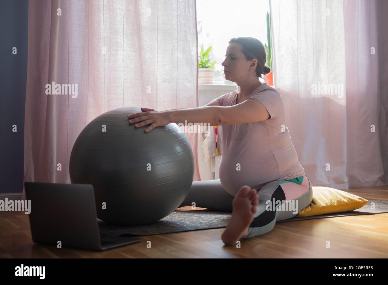 Pregnant woman in sportswear, doing yoga, pilates training, Wide Angle Seated Forward Bend pose, Upavishtha Konasana Stock Photo