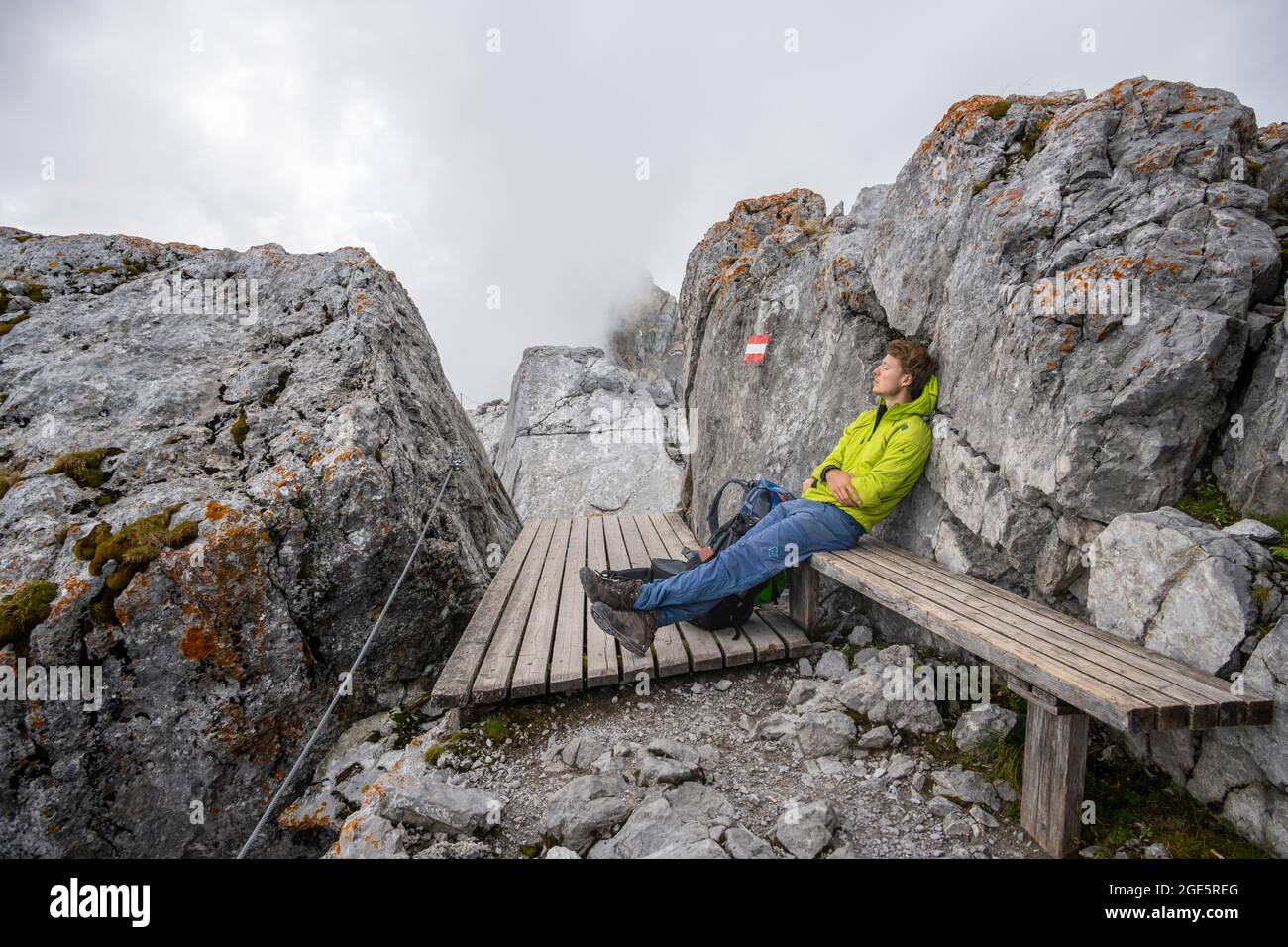Hiker sits tired on a bench and sleeps, hiking trail to the Watzmann, Watzmann crossing, Berchtesgaden, Bavaria, Germany Stock Photo