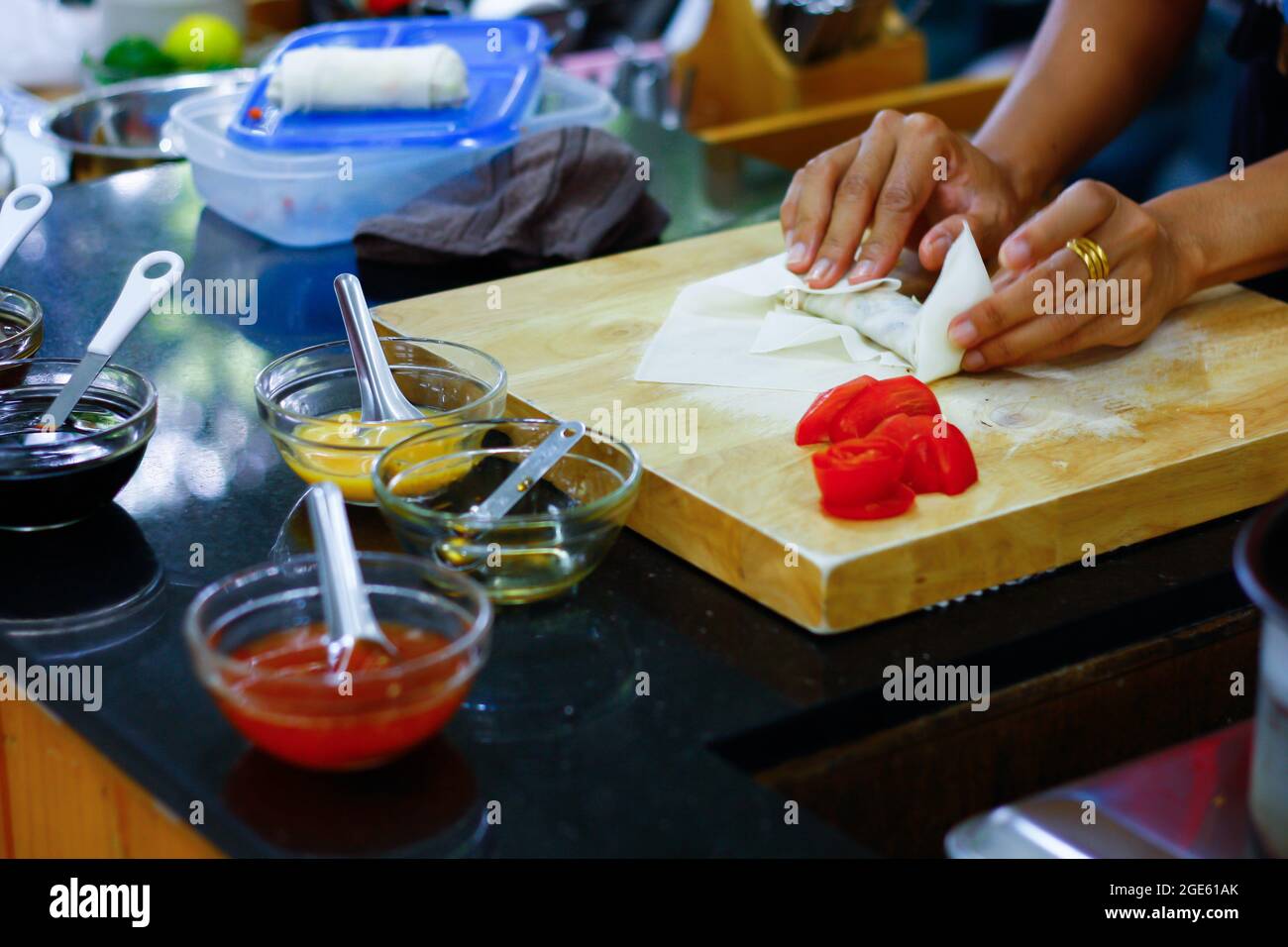 Photo Asian woman hands wrapping spring rolls on chopping board in ...