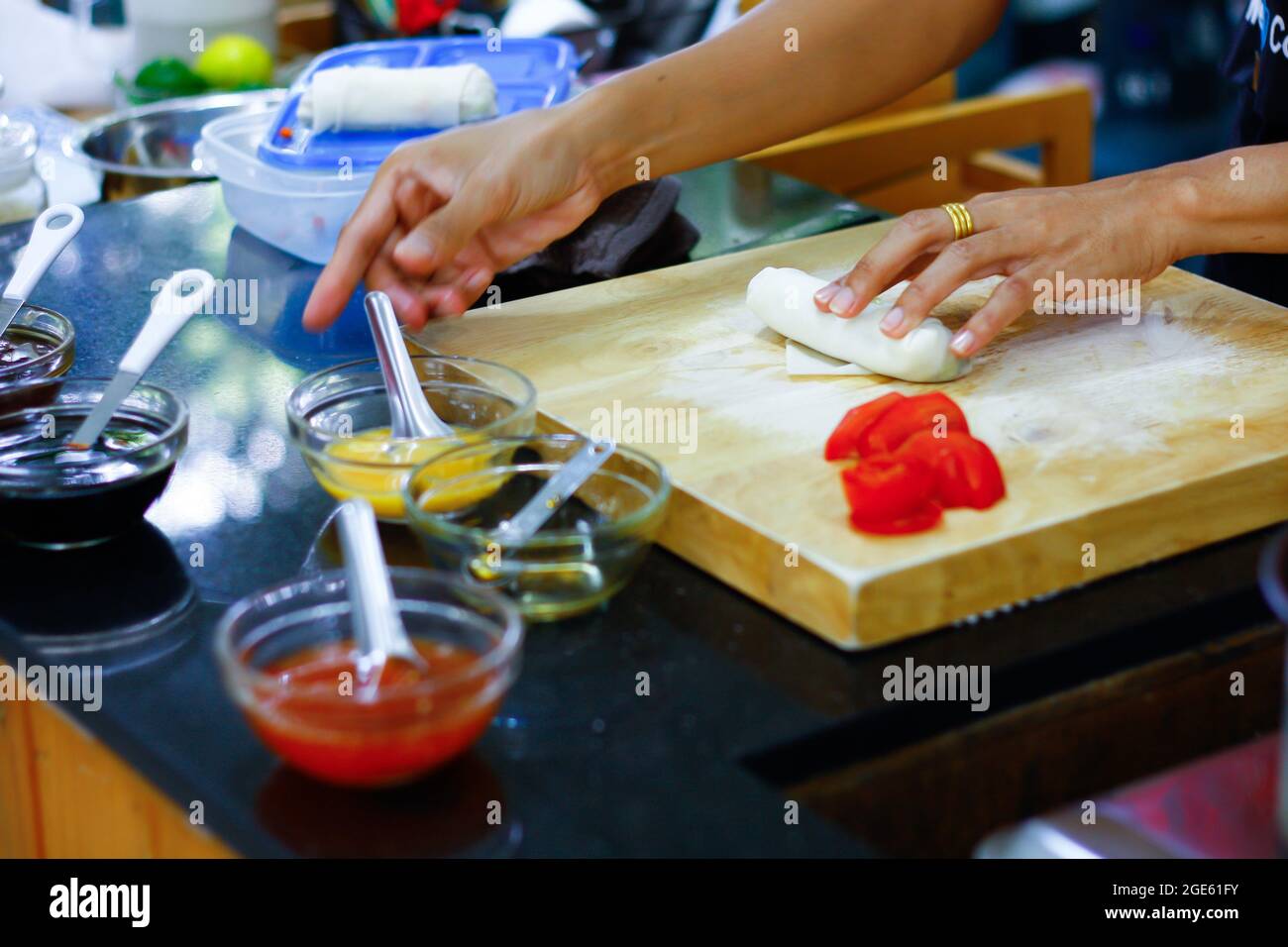 Photo Asian woman hands wrapping spring rolls on chopping board in ...