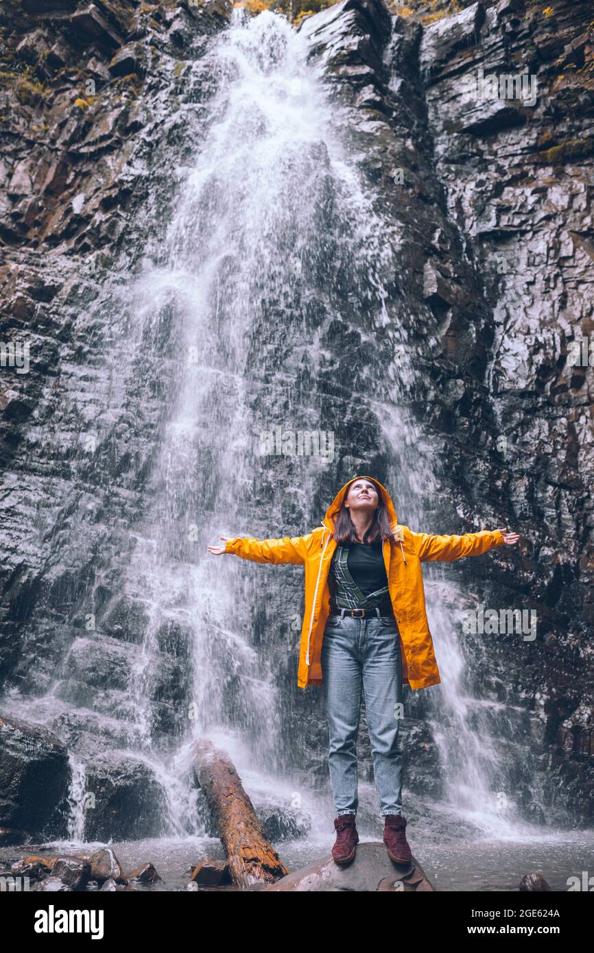 woman in yellow raincoat at autumn waterfall hiking concept Stock Photo ...