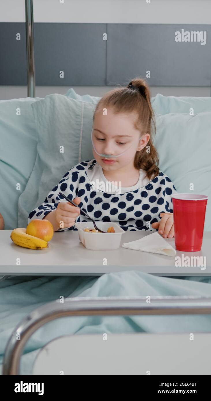 Mother sitting with sick child patient while eating healthy food lunch