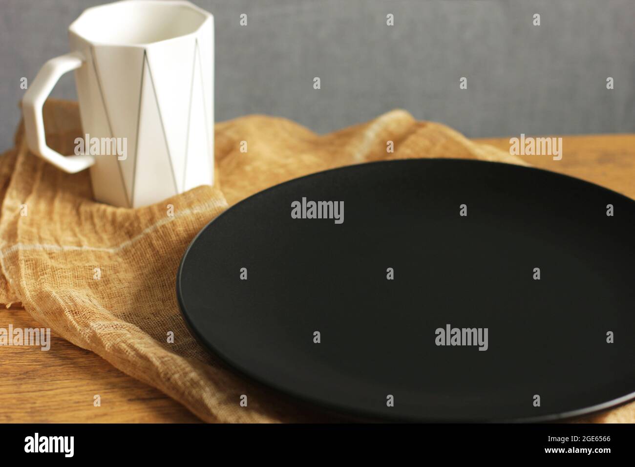 Empty black plate and white cup. Empty dishes. Minimalistic set of dishes. Plate without food Stock Photo