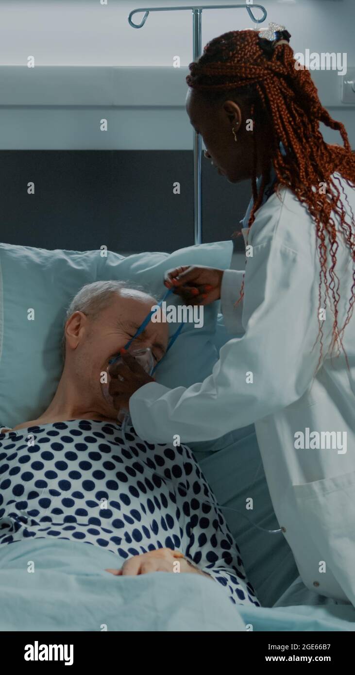 Multi ethnic nurse and doctor helping sick patient in hospital ward with  nasal oxygen tube, consulting stethoscope and monitor. Old man getting  emergency reanimation in intensive room Stock Photo - Alamy