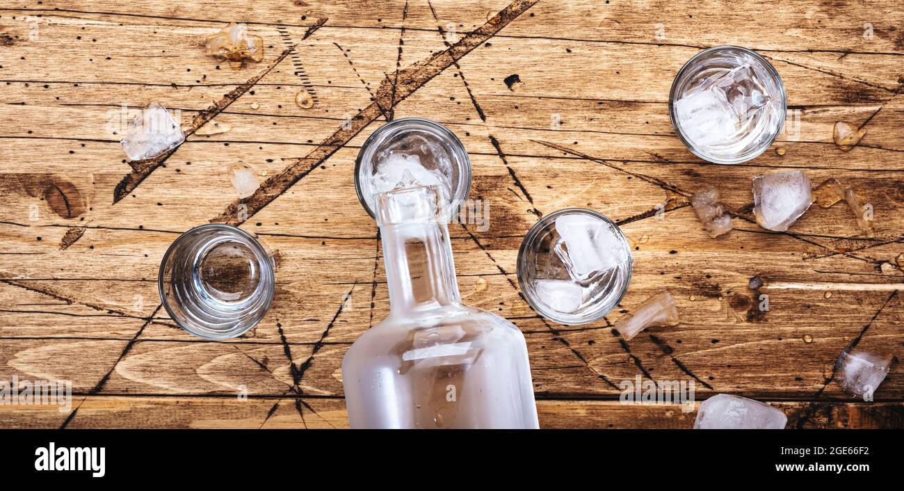 Russian vodka in shot glasses on wooden table, iced strong alcohol drink in misted glass. Top view, negative space Stock Photo