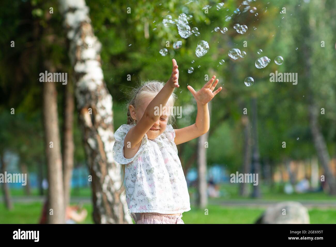 Little cute girl in the summer park blowing bubbles and having fun ...