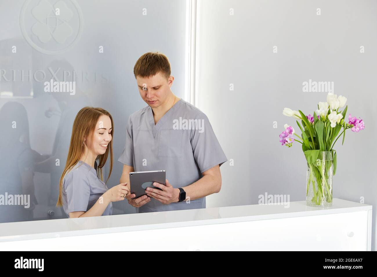 Dentist with dental nurse in modern dental office using tablet pc wearing uniform. Orthodontic specialist and assisant at reception in dental clinic d Stock Photo