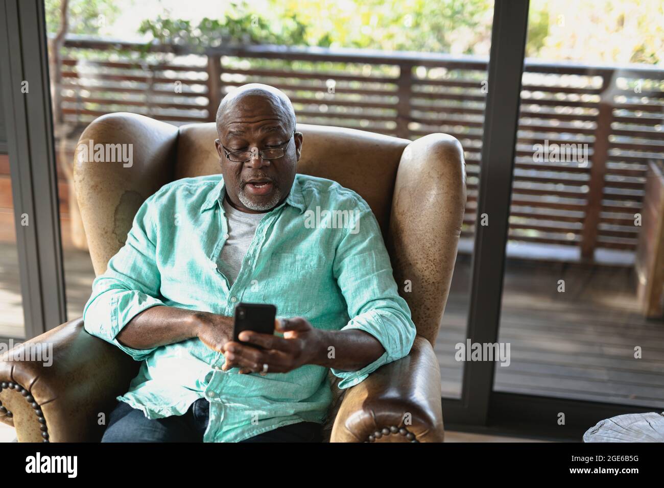 Senior african american man sitting on the armchair and using smartphone in the modern living room Stock Photo
