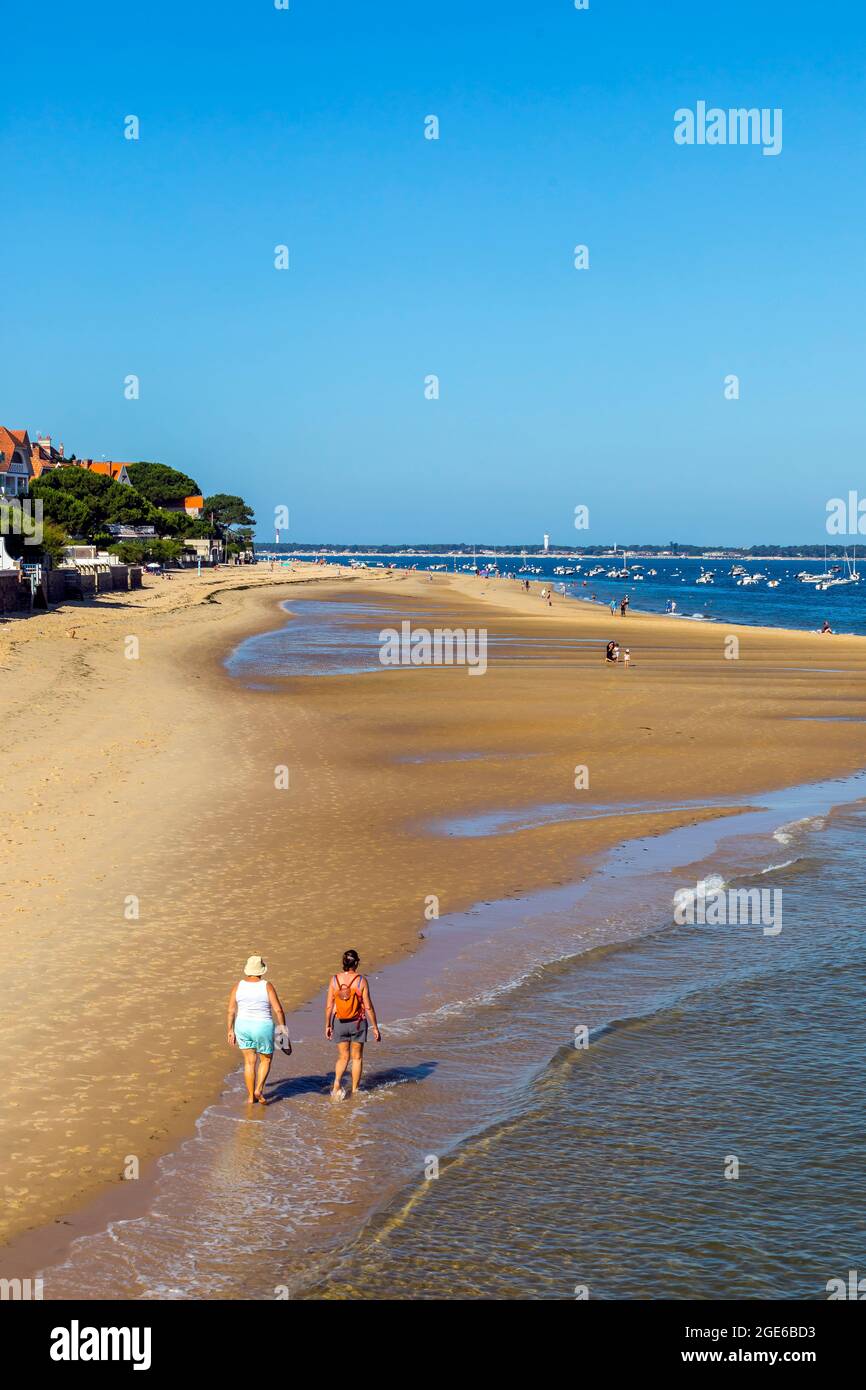Arcachon (south western France): tourists walking on the Pereire Beach at low tide. Tourists on the beach with houses and buildings along the waterfro Stock Photo