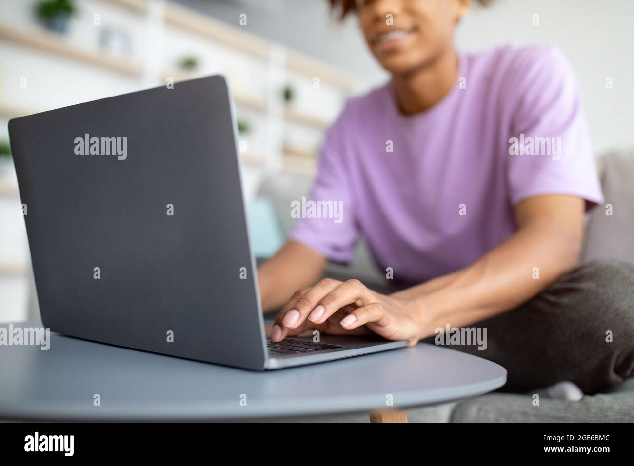 Web based schooling. Cropped view of black teen guy using laptop, speaking to friends on webcam, making home assignment indoors. Unrecognizable adoles Stock Photo