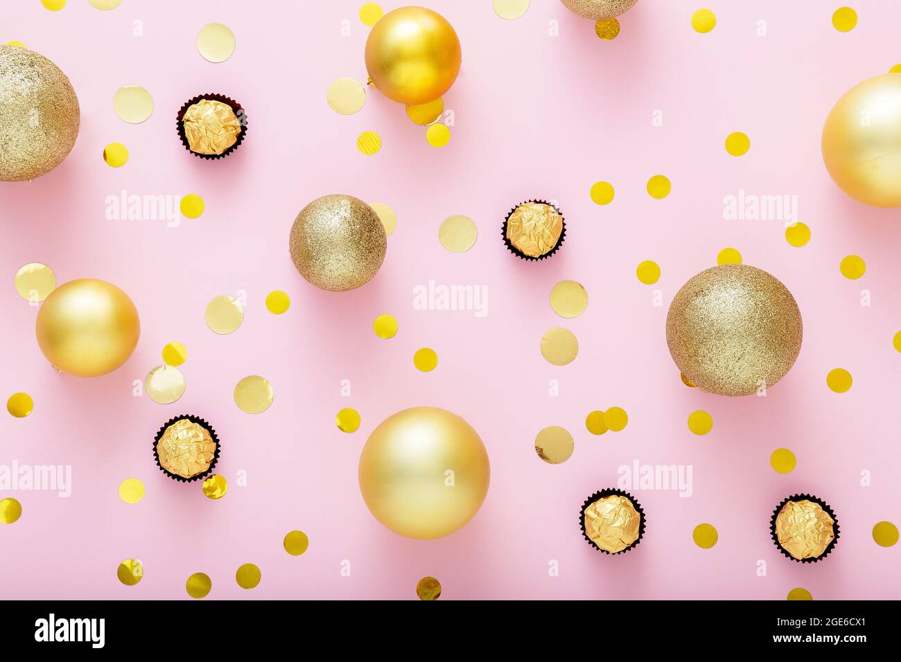 Pink festive Christmas background with Golden christmas decorations with sweets Candies Golden confetti on pink color background. Background texture Stock Photo