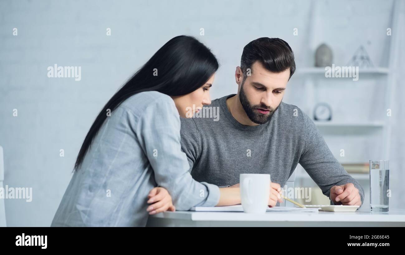 couple discussing finances and looking at calculator on table Stock Photo