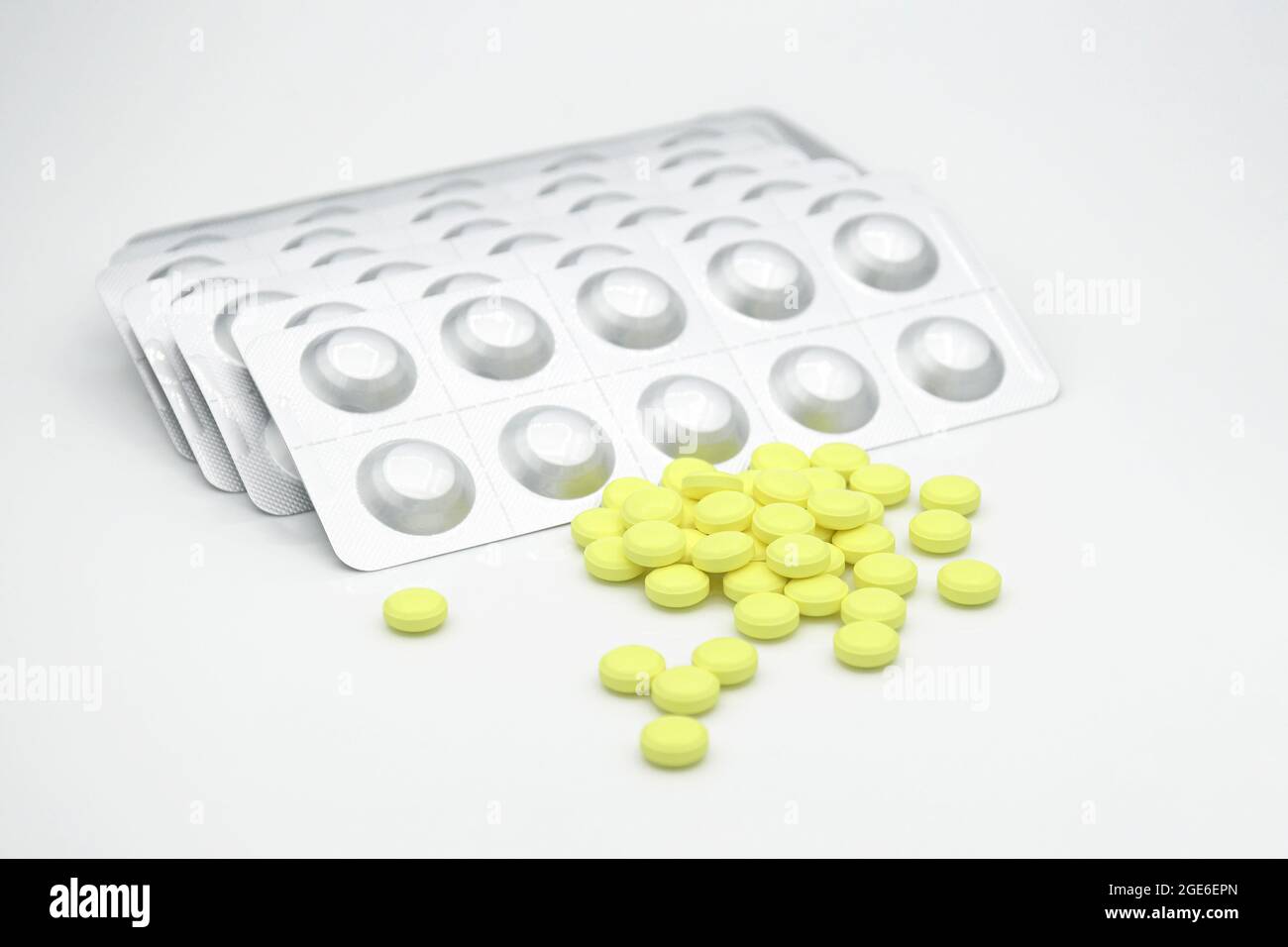 Yellow round film-coated tablet with aluminium hard strip on white background. Some oral dosage form of Favipiravir, antiviral agents. Stock Photo