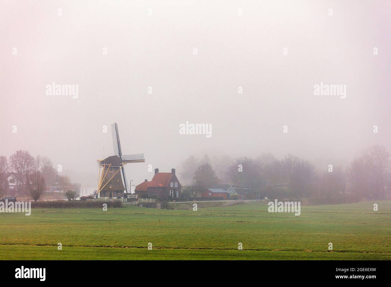 The Netherlands, Nigtevecht, Windmill along Vecht river. Morning mist. Stock Photo