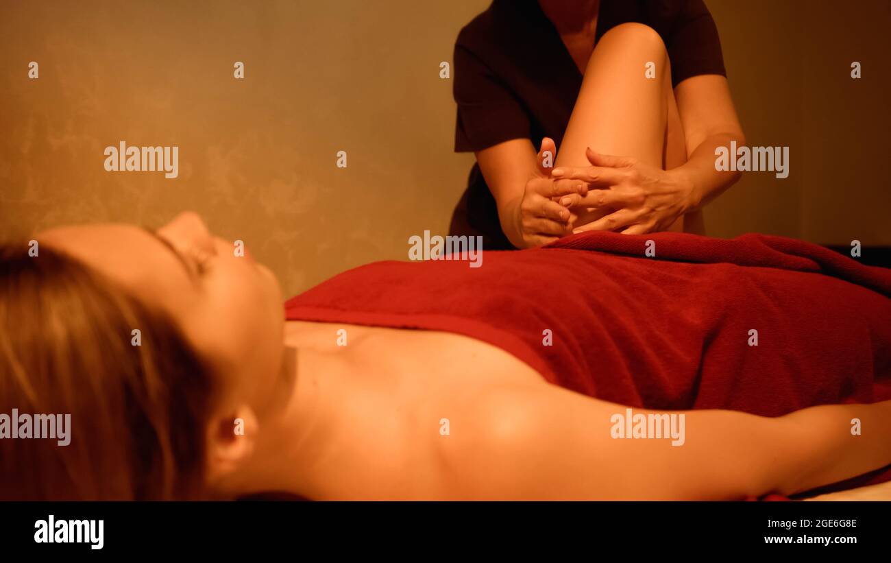 masseur massaging leg of young woman on massage table Stock Photo