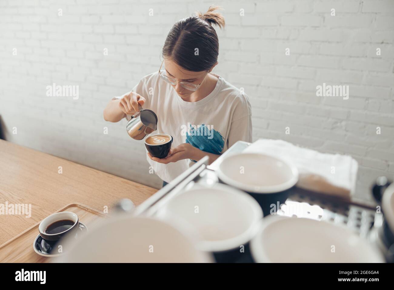 Nice female barista making latte art in cafeteria Stock Photo