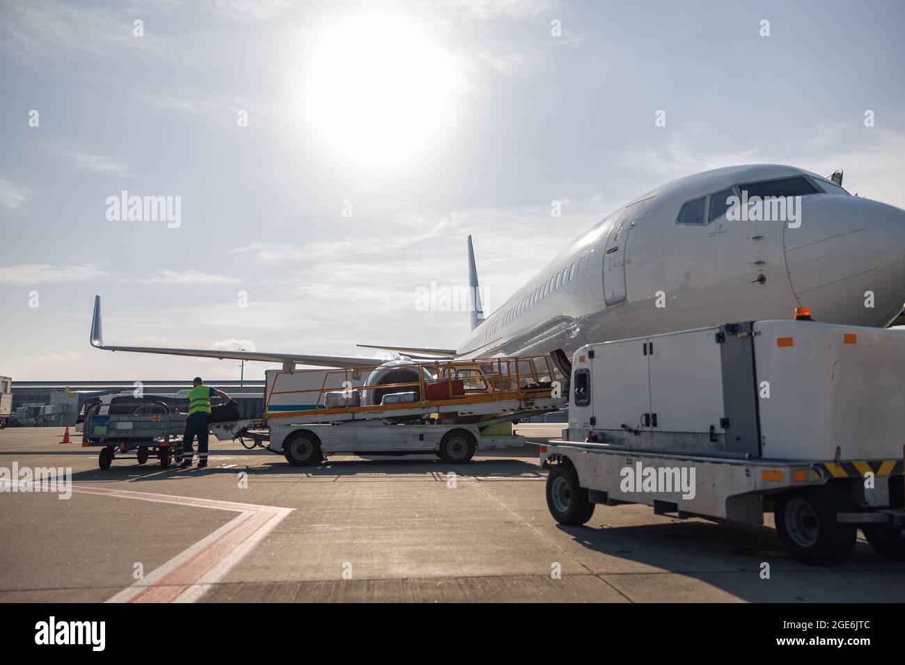 Worker loading baggage on conveyor belt to an airplane outdoors on a daytime Stock Photo Alamy