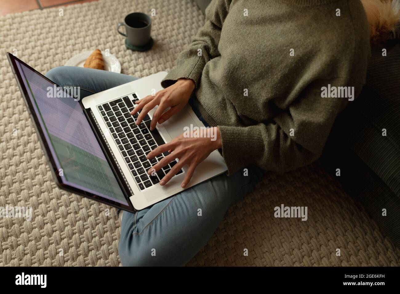 Caucasian woman in living room, sitting on floor, working using laptop ...