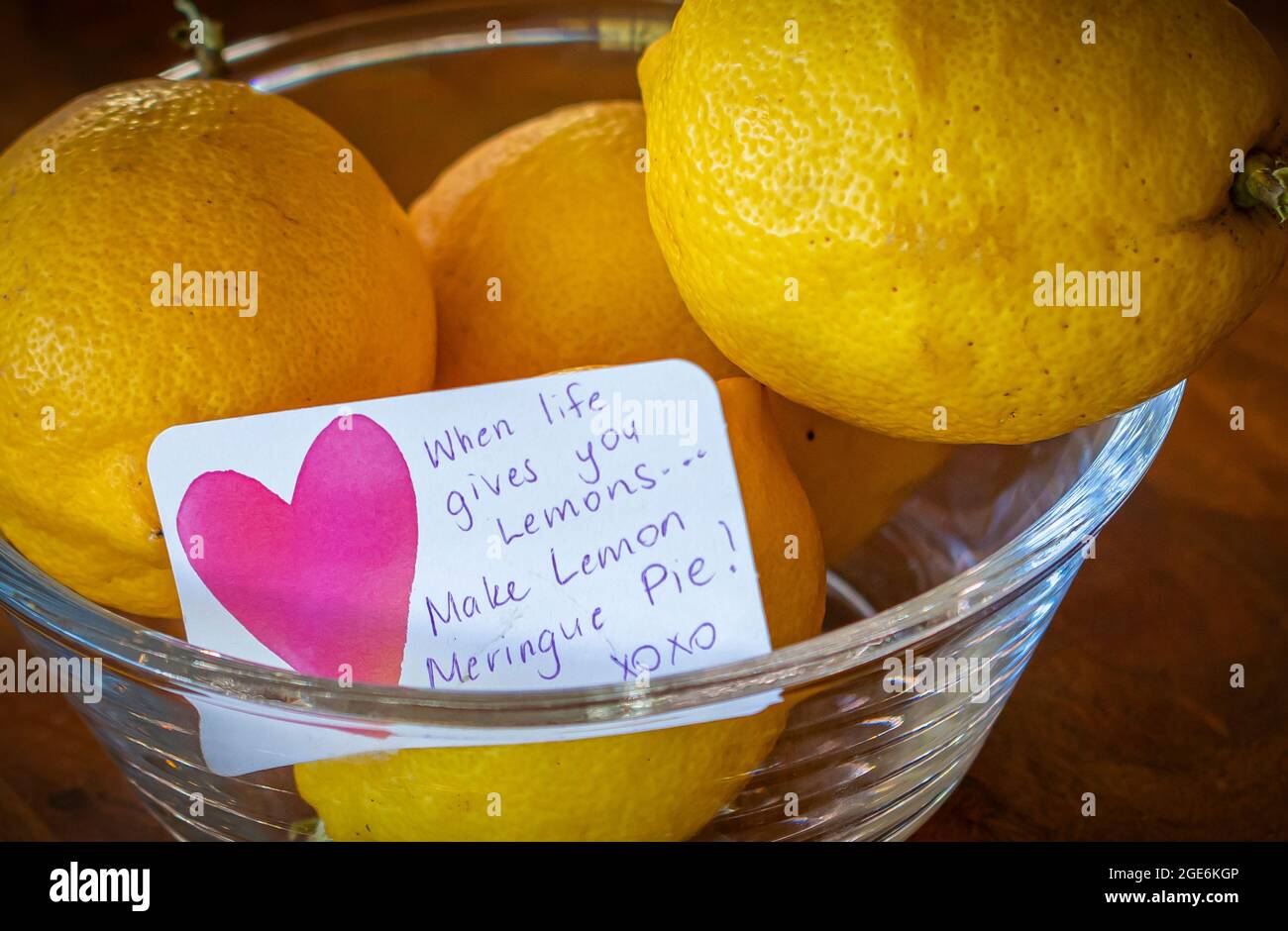 Yellow lemons in a glass bowl with note, when life gives you lemons