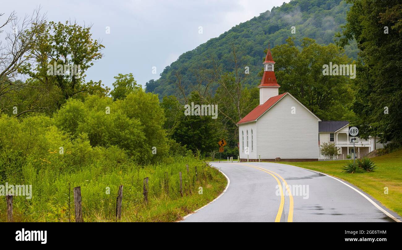 A small church sits alongside a country road near a hillside of green forest in rural Virginia. Stock Photo