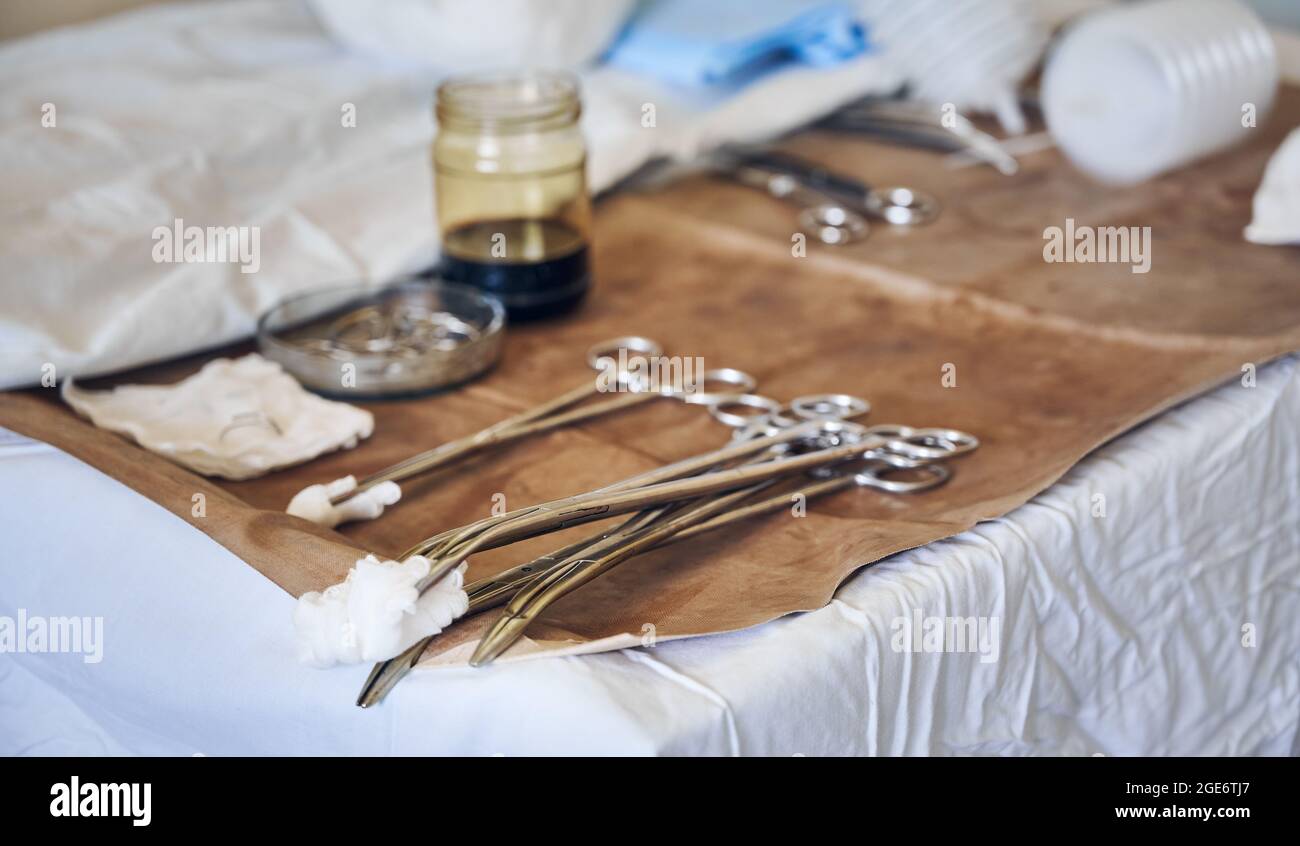 Close up of stainless steel forceps with tampons on brown medical cloth.  Set of tools for plastic surgery in operating room. Concept of aesthetic  plastic surgery and medical instruments Stock Photo -
