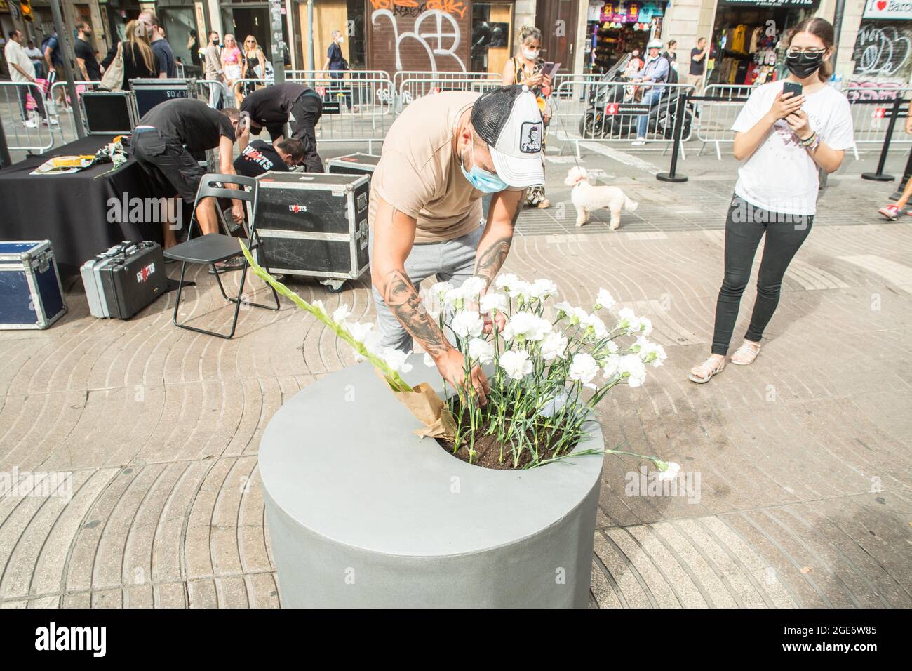 Barcelona, Catalonia, Spain. 17th Aug, 2021. Person is seen depositing flowers to the victims of the Las Ramblas attack in Barcelona.Barcelona pays tribute to the victims on the fourth anniversary of the jihadist attack on La Rambla where on August 17, 2017, a van carried out the massive outrage, which caused the death of 15 people.The families of the victims have been the protagonists of the ceremony, depositing white carnations and bouquets of flowers in three cylinders. This was followed by the authorities, with the mayor of Barcelona, Ada Colau, the president of the Generalitat of Catal Stock Photo