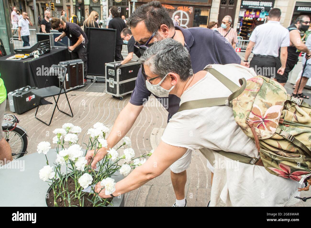 Barcelona, Catalonia, Spain. 17th Aug, 2021. People are seen laying flowers at the victims of the Las Ramblas attack in Barcelona.Barcelona pays tribute to the victims on the fourth anniversary of the jihadist attack on La Rambla where on August 17, 2017, a van carried out the massive outrage, which caused the death of 15 people.The families of the victims have been the protagonists of the ceremony, depositing white carnations and bouquets of flowers in three cylinders. This was followed by the authorities, with the mayor of Barcelona, Ada Colau, the president of the Generalitat of Cataloni Stock Photo