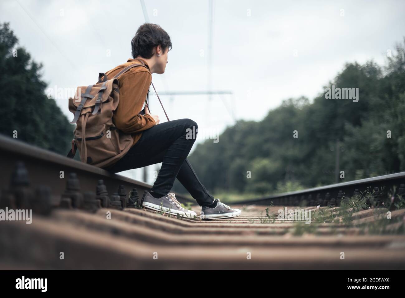 Photographer in brown jacket with backpack and retro camera on railroad Stock Photo