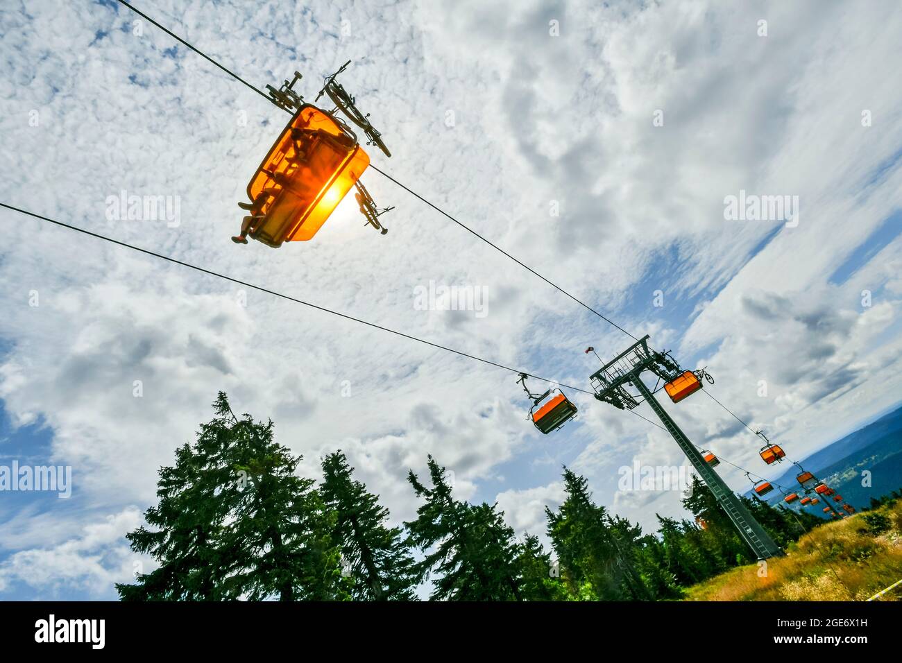 chairlift with orange cable cars in summer contra light Stock Photo