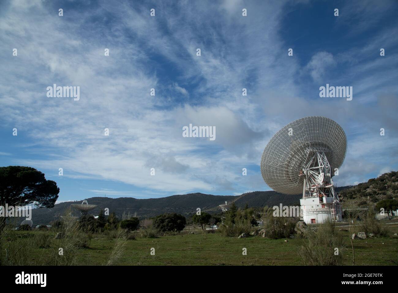 Giant radio telescopes located in valley between mountains with blue sky and clouds Stock Photo