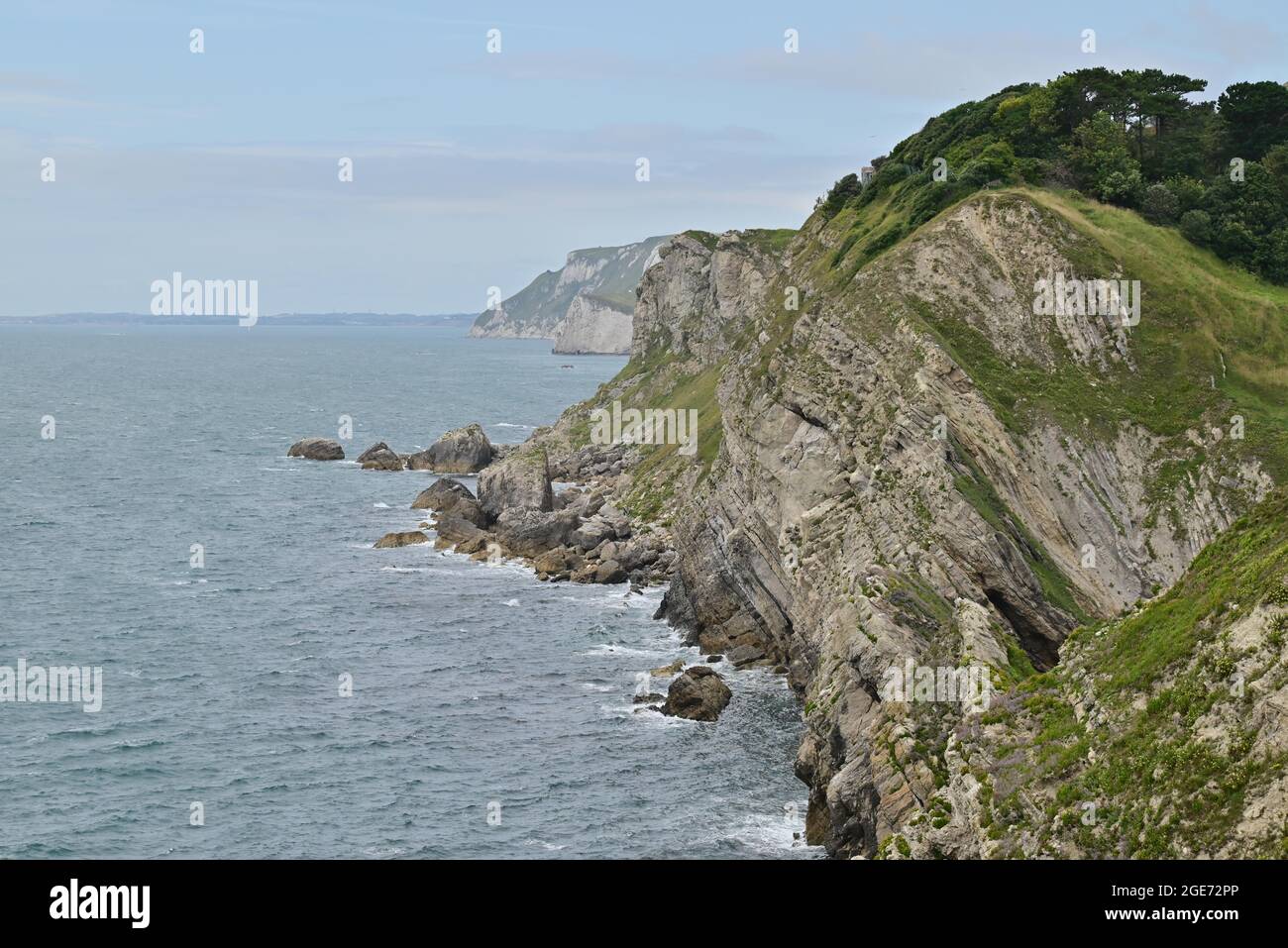 Lulworth Cove, Dorset, UK, 17th August 2021, Weather. Summer continues in a disappointingly cool vein but clouds eventually give way to bright sunshine on the Jurassic Coast. Looking west along the rugged coastline. Credit: Paul Biggins/Alamy Live News Stock Photo