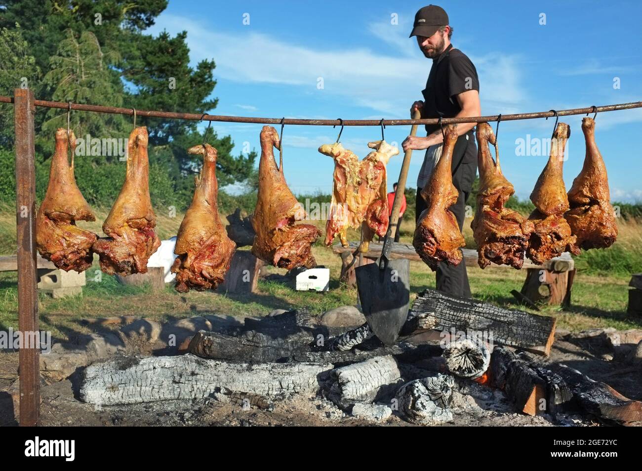 Legs of lamb cooking above an open fire in Suffolk, England Stock Photo