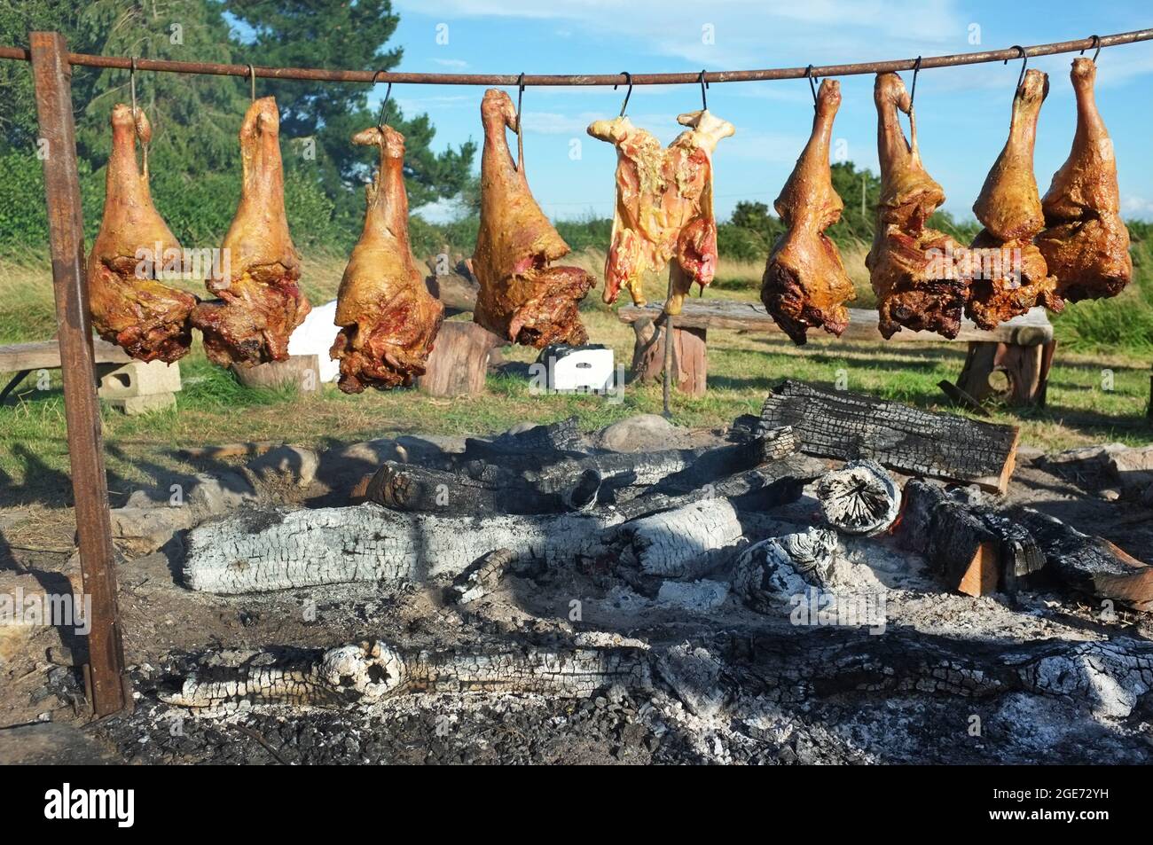 Legs of lamb cooking above an open fire in Suffolk, England Stock Photo