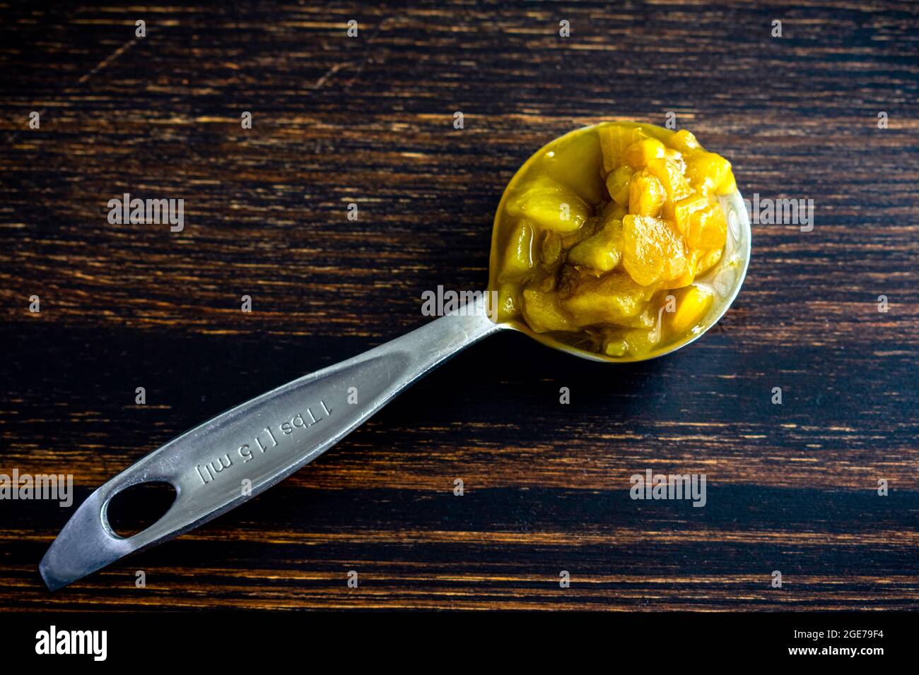 Tablespoon of Canned Hatch Green Peppers: A measuring spoon filled with diced green New Mexico chili peppers Stock Photo