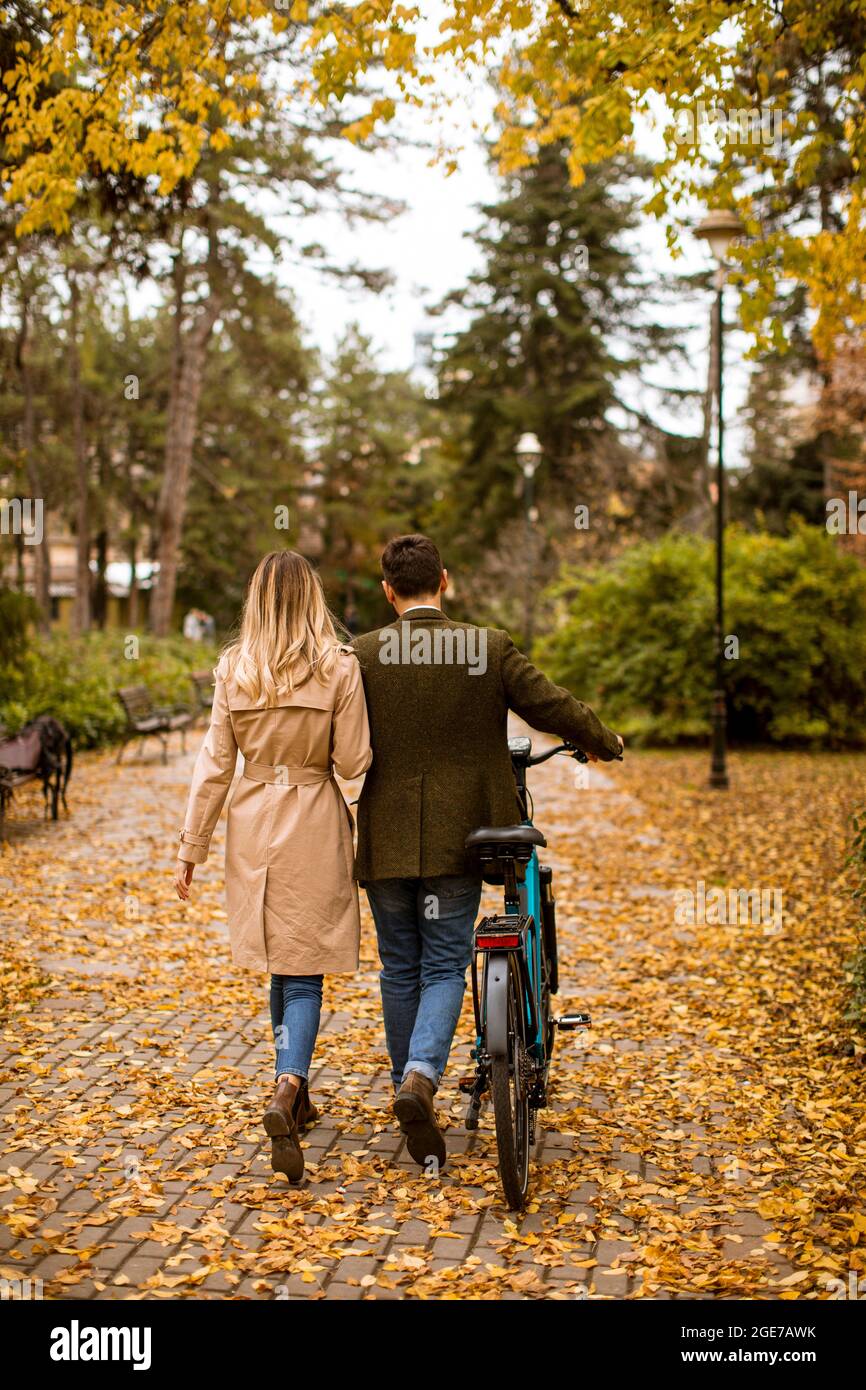 Rear view at handsome young couple in the autumn park with electrical ...