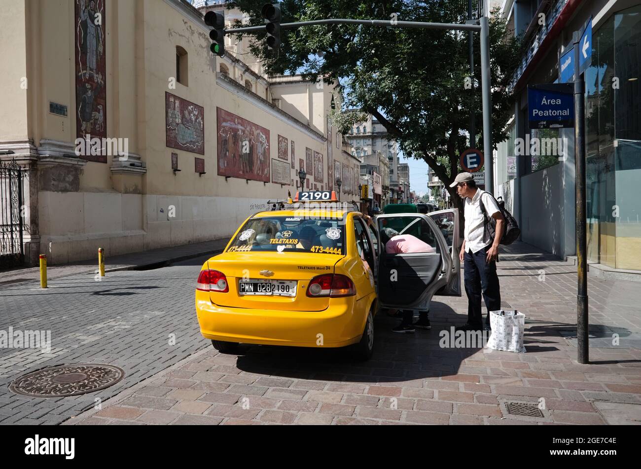 Cordoba, Argentina - January, 2020: Man gets into taxi on Bernardino Rivadavia street near church called Basilica Nuestra Senora de La Merced at inter Stock Photo